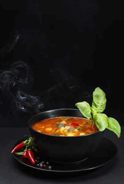 Tomato soup decorated with basil leaf on black background — Stock Image Tomato soup decorated with basil leaf on black background Stock Photo