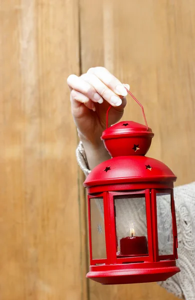 Woman holding red christmas lantern. Wooden wall in the back — Stock Photo, Image