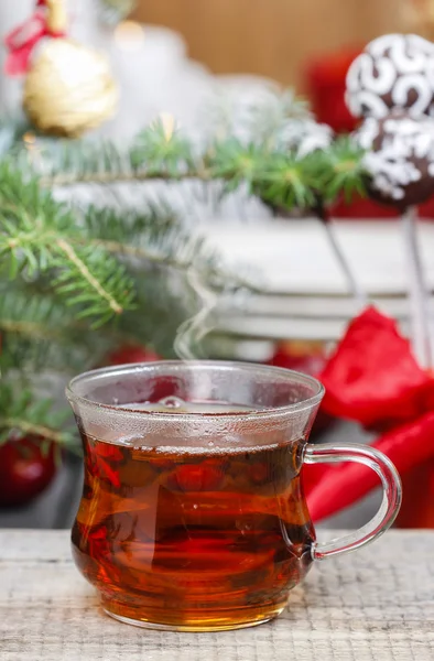 Glas varm dampende te blandt juledekorationer - Stock-foto