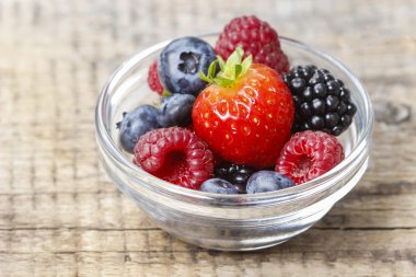 ahşap masa üzerinde küçük şeffaf kase meyve salatası