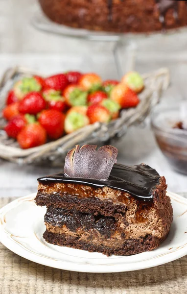 Schokoladenkuchen und Korb mit frischen rohen Erdbeeren im Rücken — Stockfoto