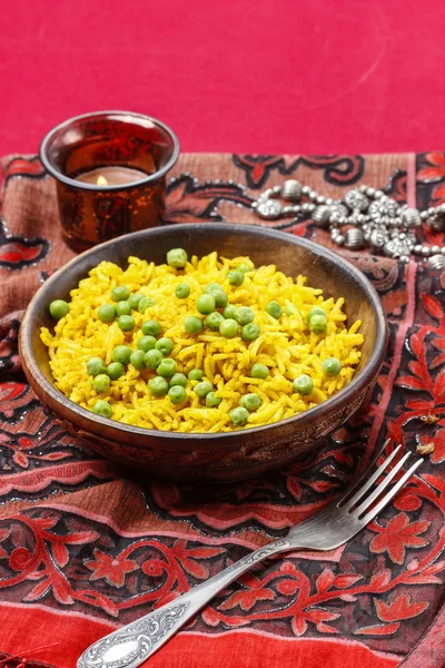 Indiase keuken: kom van gele rijst met groene erwten op rode backg — Stockfoto