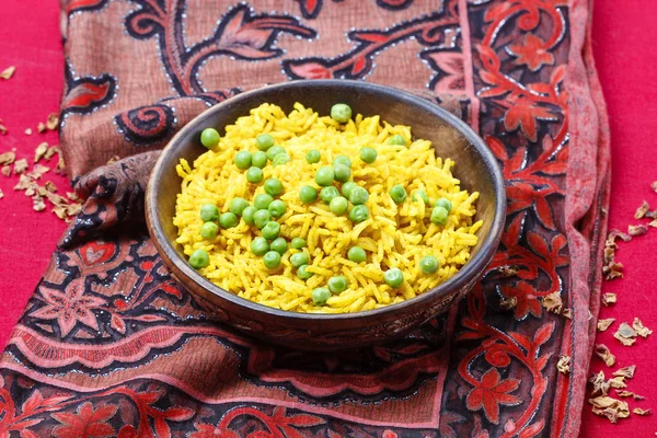 Indiase keuken: kom van gele rijst met groene erwten op rode backg — Stockfoto