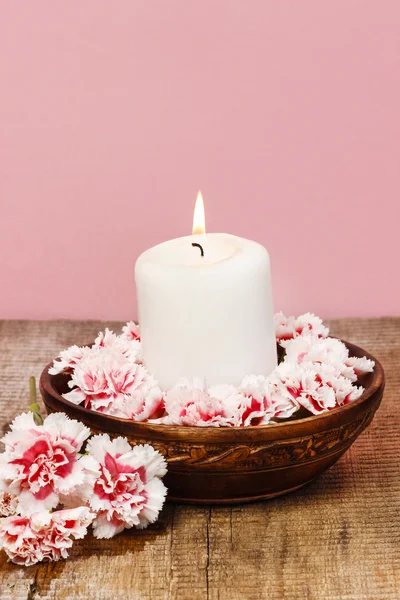 White candle among carnation flowers in vintage wooden bowl — Stock Photo, Image