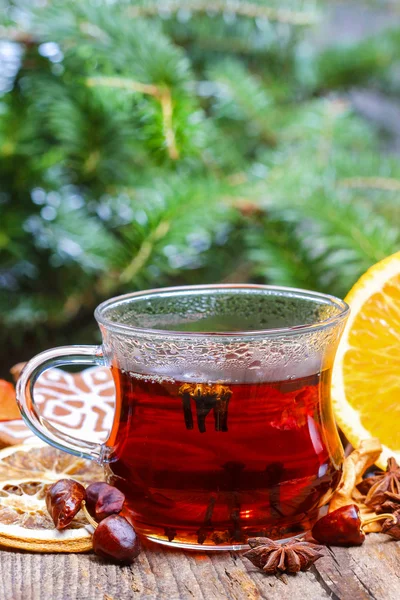 Glass of hot steaming tea among christmas decorations on wooden