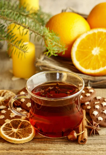 Glass of hot steaming tea among christmas decorations on wooden — Stock Photo, Image