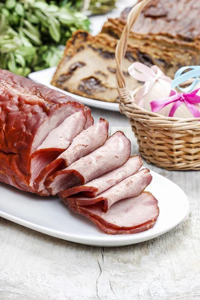 Sliced sausage on wooden table. Wicker basket of easter eggs — Stock Photo, Image