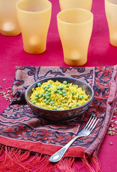 Indian cuisine: bowl of yellow rice with green peas on red — Stock Photo, Image