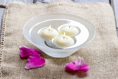 gül yaprakları arasında suda yüzen mumlar. Aromaterapi Spa