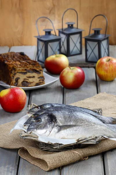 Gilt-head bream fishes in wicker basket on wooden table. — Stock Photo, Image
