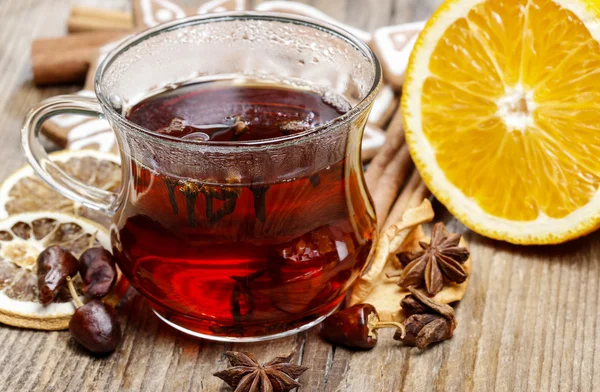 Glass of hot steaming tea among christmas decorations on wooden — Stock Photo, Image