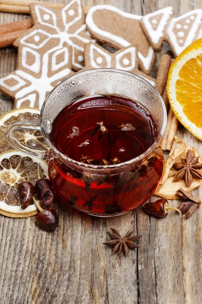 Glass of hot steaming tea among christmas decorations on wooden — Stock Photo, Image