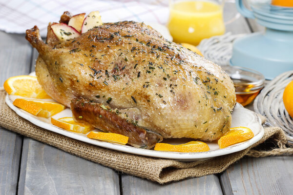 Жареная утка с апельсинами на деревянном столе
