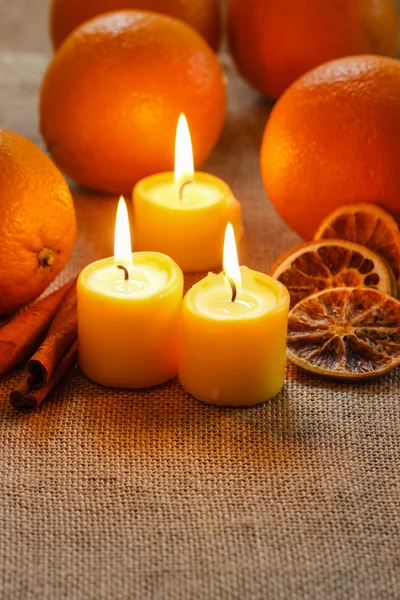 Hermosas velas y naranjas jugosas en manteles de yute —  Fotos de Stock