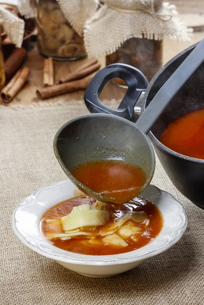 A servir sopa de tomate. Derramando sopa em uma chapa — Fotografia de Stock