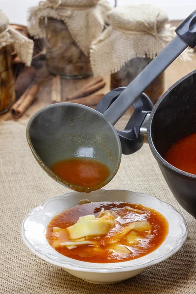 A servir sopa de tomate. Derramando sopa em uma chapa — Fotografia de Stock