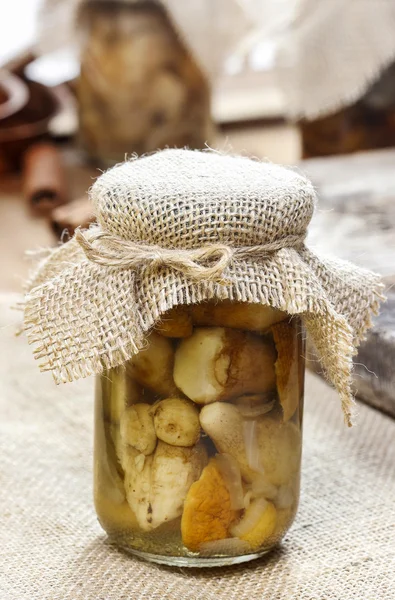 Pot en verre de champignons marinés sur une nappe en jute — Photo