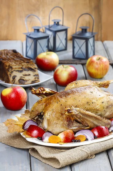 Roasted goose with apples and vegetables on wooden table. — Stock Photo, Image