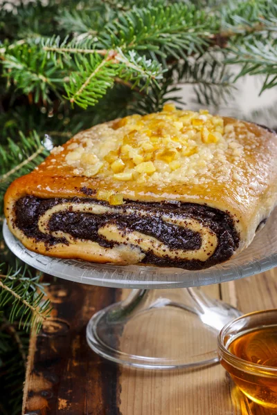 Torta di semi di papavero su supporto torta di vetro sotto ramo di abete — Foto Stock