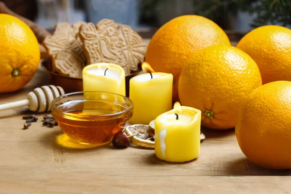 Krásné svíčky, misky medu a čerstvé oranžové ovoce na dřevo — Stock fotografie