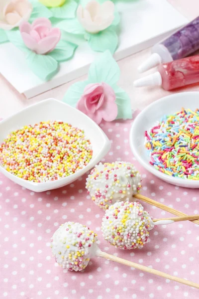 White cake pops on pink dotted table cloth. Colorful sprinkles — Stock Photo, Image