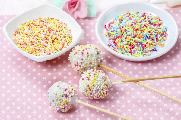 White cake pops on pink dotted table cloth. Colorful sprinkles — Stock Photo, Image