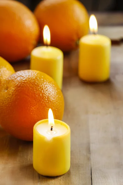 Beautiful candles and juicy oranges on wooden table