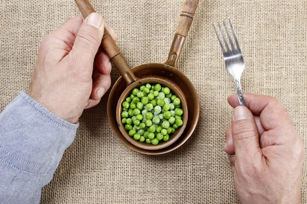 Un affamé qui mange des pois verts. Symbole de minceur — Photo