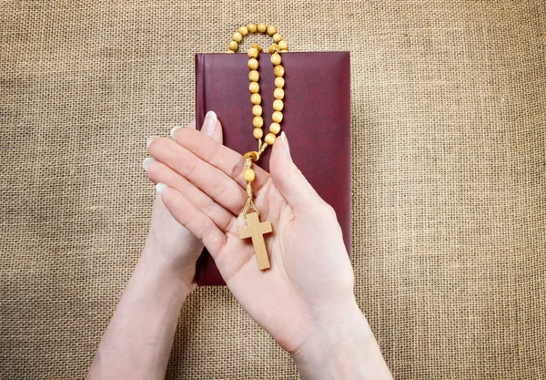 Manos sosteniendo la antigua Santa Biblia y rosario marrón de madera —  Fotos de Stock