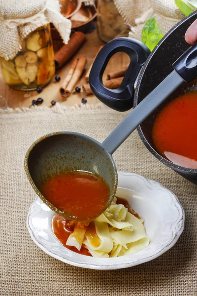 A servir sopa de tomate. Despejar sopa em um prato — Fotografia de Stock