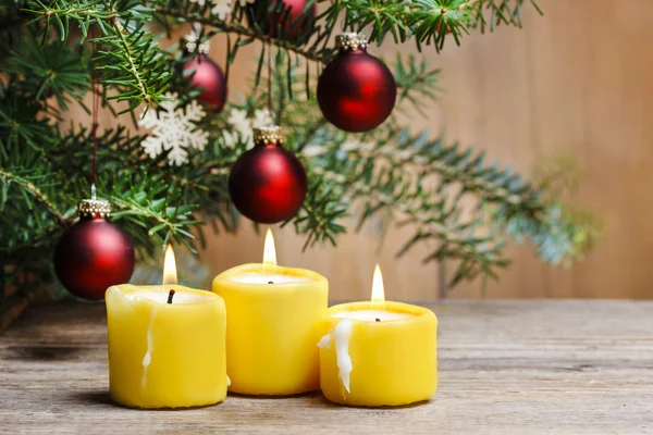 Velas amarillas frente al árbol de Navidad . — Foto de Stock