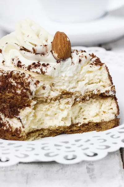 Tiramisu-Kuchen auf weißem Teller. Holzhintergrund, selektiver Fokus — Stockfoto