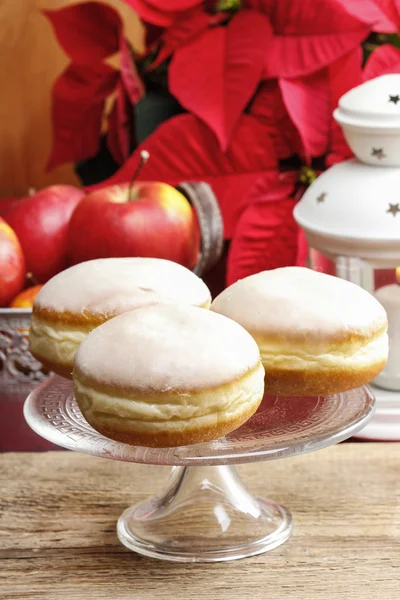 Donuts op taart stand. Kerstmis instelling, poinsettia in de backg — Stockfoto