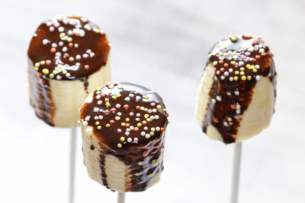 Banana cake pops with chocolate and colorful sprinkles — Stock Photo, Image