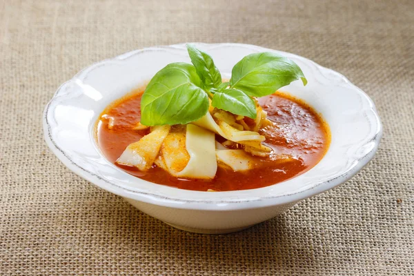 Jüt masa örtüsü üzerinde beyaz tabakta domates ve biber çorbası — Stok fotoğraf