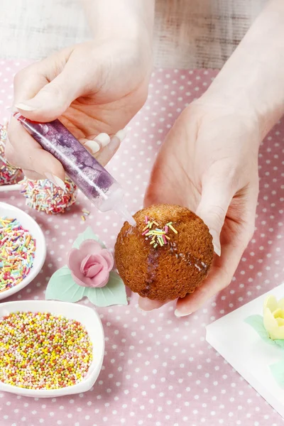 Žena, zdobení muffiny — Stock fotografie