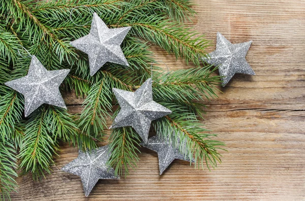 Shiny silver stars on fir branch. Wooden background, copy space — Stock Photo, Image