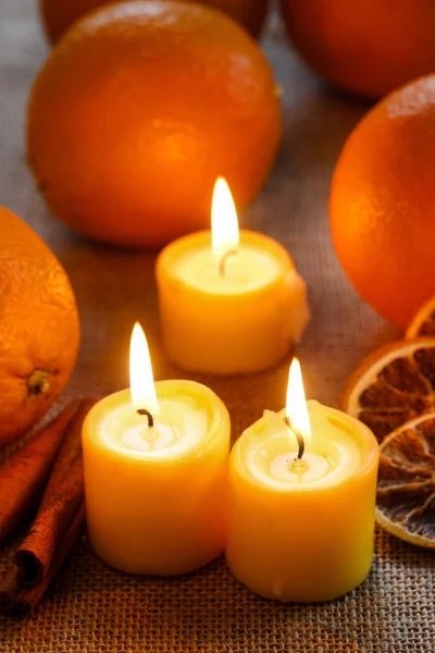 Hermosas velas y naranjas jugosas en manteles de yute — Foto de Stock