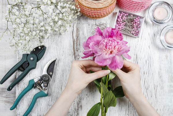 Флорист на работе. Женщина делает весенние цветочные украшения
