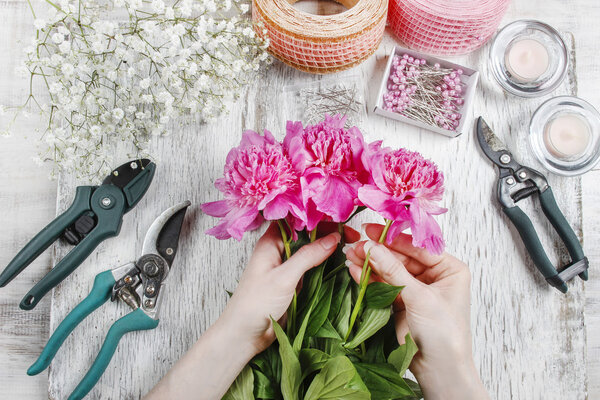 Флорист на работе. Женщина делает весенние цветочные украшения
