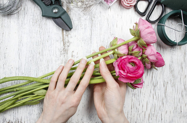 Флорист на работе. Женщина делает красивый букет из розового персидского
 