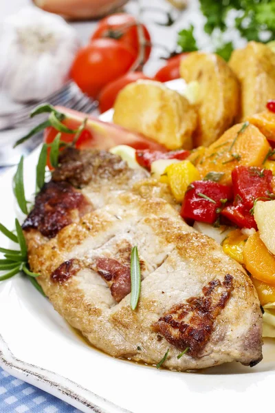 Joint of pork with baked potatoes and fresh vegetables Royalty Free Stock Images