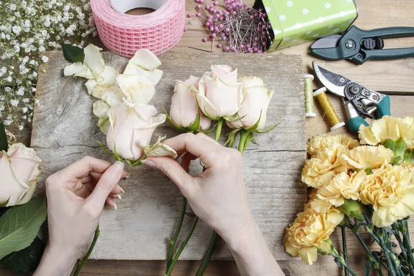 Florista en el trabajo. Mujer haciendo ramo de boda de rosas rosadas y — Foto de Stock