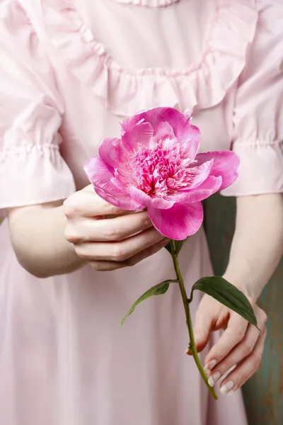 Mujer en vestido rosa sosteniendo impresionante peonía rosa — Foto de Stock