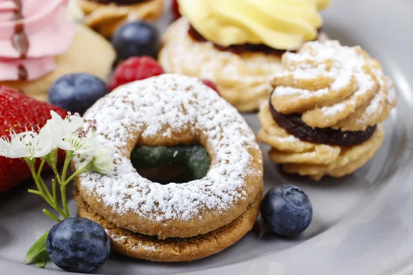 Assorted cookies and fruits on grey ceramic plate — Stock Photo, Image