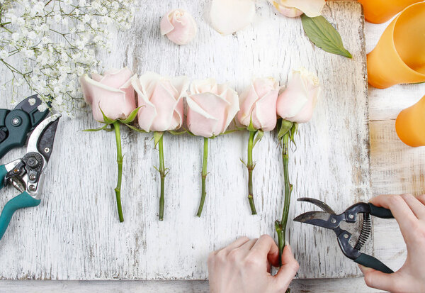 Флорист на работе. Женщина делает букет из розовых роз
