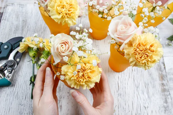 Florist at work. Woman making bouquet of pink roses and yellow c