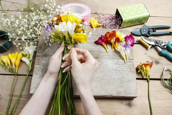 Florista no trabalho. Mulher fazendo buquê de flores freesia — Fotografia de Stock