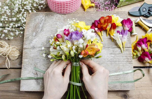 Florist at work. Woman making bouquet of freesia flowers
