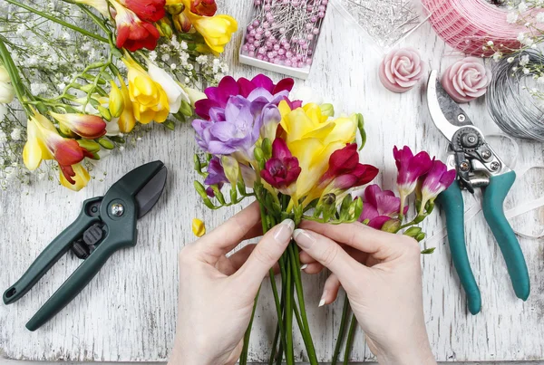 Florista no trabalho. Mulher fazendo buquê de flores freesia — Fotografia de Stock